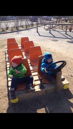 two young boys sitting on seats in the sand