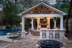 an outdoor kitchen next to a pool with a bbq and grill in the middle