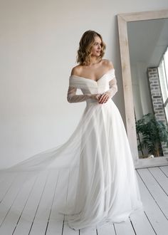 a woman in a white wedding dress standing next to a mirror