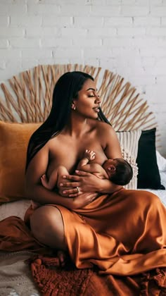 a woman holding a baby on top of a bed