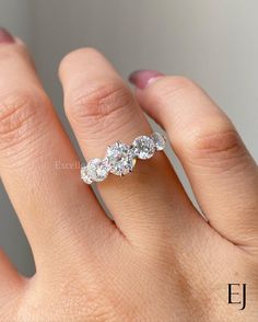 a woman's hand with a three stone diamond ring on her left hand,