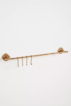 a pair of gold ear hooks hanging from a hook on a white wall, with the end of an eyeball