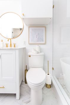 a white bathroom with marble floors and gold accents on the vanity, toilet and tub