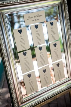 a silver frame with seating cards attached to the sides and hearts on each side, sitting in front of a window