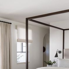 a bedroom with a four poster bed and white walls