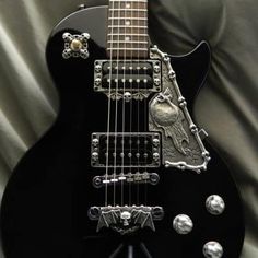 a black electric guitar sitting on top of a bed