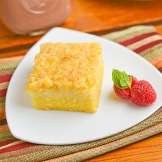 a piece of cake on a plate with raspberries next to it