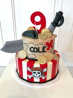 a three tiered cake decorated with pirate themed decorations and a knife sticking out of it