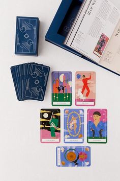 playing cards are laid out next to an open book on a white surface with blue trim