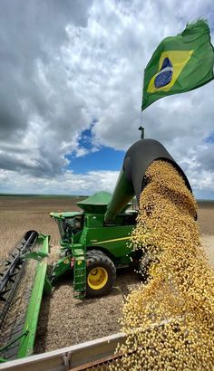 a large green machine in a field with a flag on it's back end