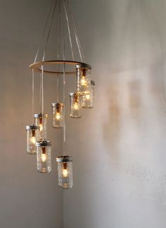 a chandelier with mason jars hanging from it's sides and lights in the middle