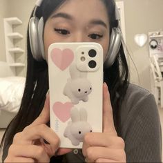 a girl wearing headphones holding up her phone case