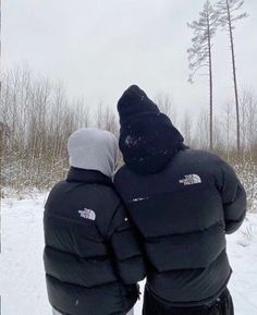 two people standing in the snow with their backs to each other