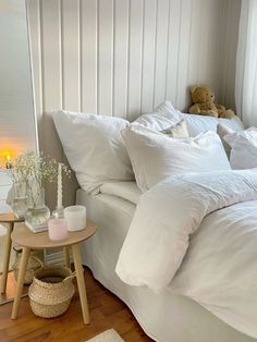 a bed with white linens and pillows in a bedroom next to a night stand