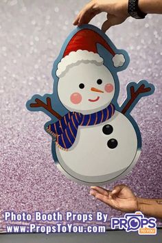 a snowman with a santa hat and scarf on it's head is being held up