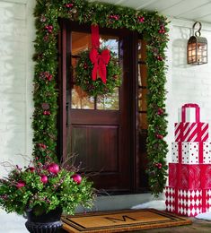 christmas decorations on the front door of a house with wreaths and presents in pots