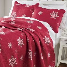 a bed with red and white snowflakes on the comforter, pillows and blanket