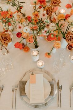 the table is set with flowers and candles