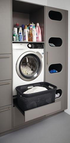 a washer sitting inside of a dryer next to a shelf filled with bottles