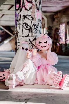 two people dressed up in costumes sitting next to each other on the ground near a tree