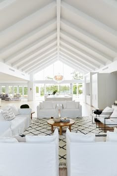 a living room filled with white furniture under a vaulted ceiling