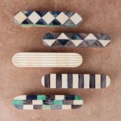 three skateboards sitting on top of a brown floor next to each other in different shapes and sizes