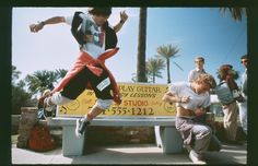 a young man jumping over a bench in front of a group of people