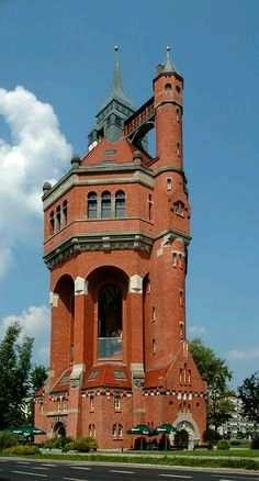 a tall red brick building with a clock on it's side and a sky background