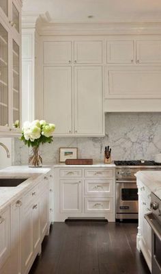 a large kitchen with white cabinets and marble counter tops, along with an oven and dishwasher