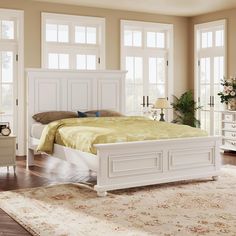 a white bed sitting on top of a wooden floor next to two dressers and a window