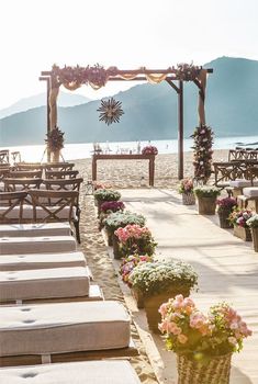 an outdoor ceremony set up on the beach with flowers in baskets and sun umbrellas