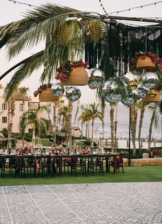 an outdoor dining area with palm trees and hanging decorations