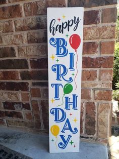 a sign that says happy birthday next to a brick wall with balloons and stars on it