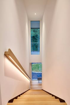 the stairs lead up to an open window in this modern house with wood flooring and white walls