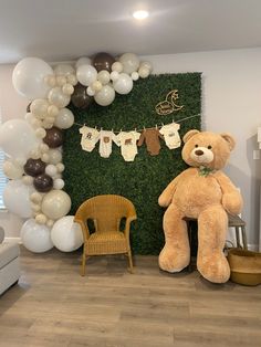 a teddy bear sitting in front of a green wall with baby ones hanging on it