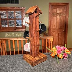 a wooden clock tower sitting on top of a counter next to a vase with flowers