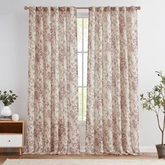 a living room with a white rug and curtains in front of a window that has pink flowers on it