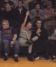 people sitting in the stands at a basketball game and one person is holding up her hand