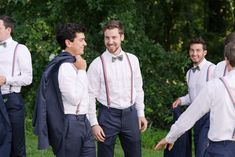 a group of young men standing next to each other in front of trees and grass