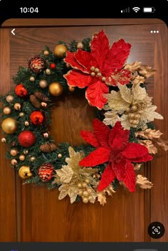 a christmas wreath with poinsettis and other decorations on a wooden door frame