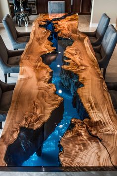 the table is made out of wood and has blue water running through it, as well as black chairs