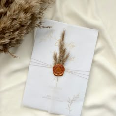 a piece of paper with a wax stamp on it sitting next to some dried grass