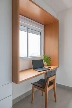 a laptop computer sitting on top of a wooden desk in front of a large window