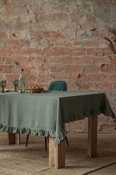 a table with a green cloth on it in front of a brick wall and rug