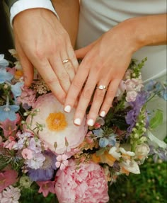 the bride and groom are holding hands with their wedding rings