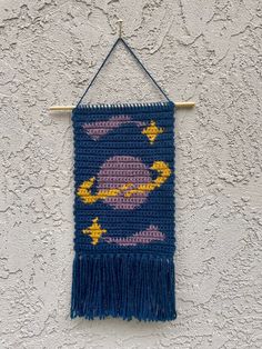 a crocheted wall hanging on the side of a building with a blue and yellow pattern