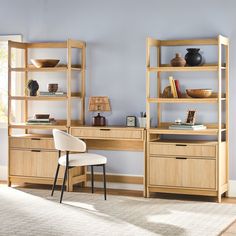 a chair and desk in a room with shelves on the wall behind it, near a window