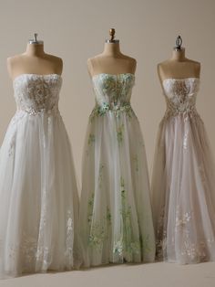 three dresses on mannequins in front of a white wall and one is wearing a flowered dress