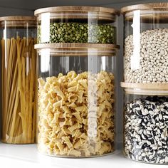 four jars filled with different types of food in each one, including pasta and noodles