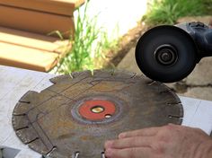 a person using a grinder to cut metal with a circular blade on top of it